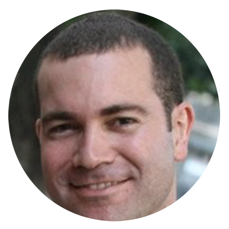 Man smiling with short hair and stubble.