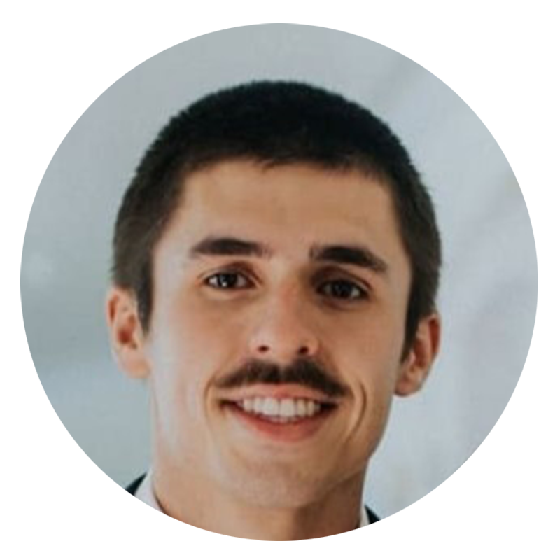 Man with a mustache smiling in a suit.